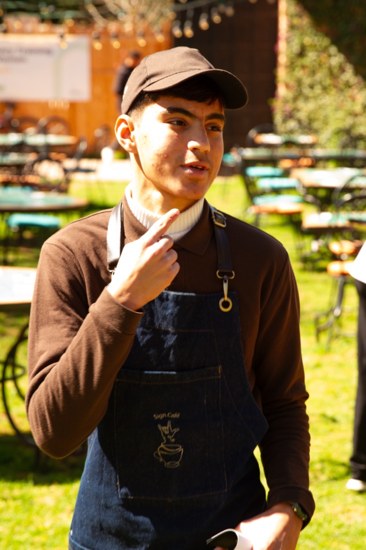 A smiling Sign Café barista
